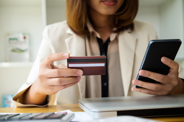 businesswoman making a payment on her phone holding credit card 