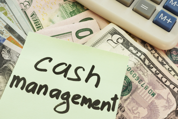 pile of cash and calculator with a stick note on top that reads "cash management" 